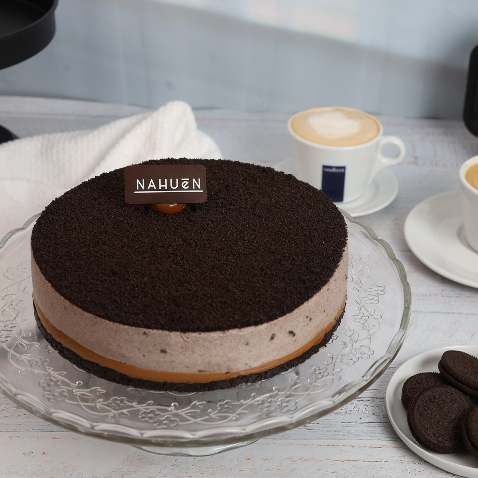 NAHUEN Gourmet Market's chocolate and dulce de leche cake, topped with cookie crumbs, next to coffee.